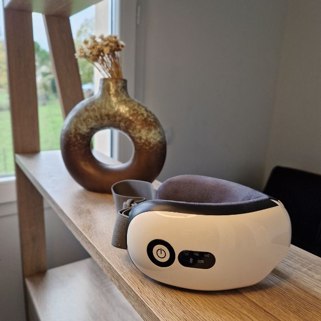 Le masseur ultimate posé sur un meuble en bois avec un pots de fleurs en arrière plan.