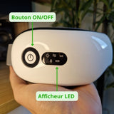 Le masseur oculaire posé sur une main, on peut voir le Bouton ON/OFF ainsi que l'afficheur led des modes vibration, chauffage et compression. On vois également le niveau de charge de la batterie et le sigle bluetooth.